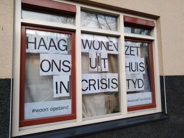 Voor het raam van de woning hangt ‘Haag Wonen zet ons uit huis in crisis tijd
